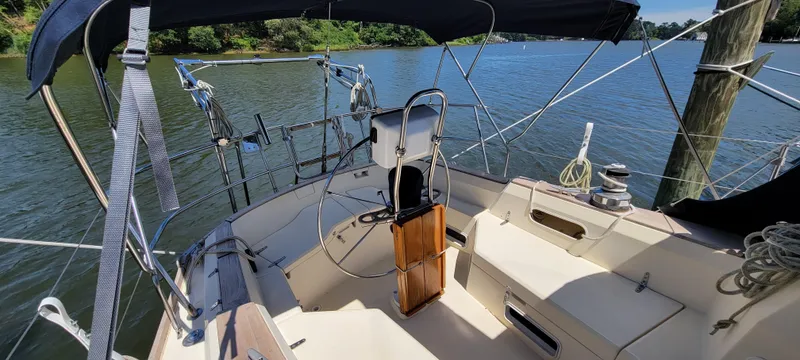 Slide: The Image of 1988 Sabre 38 MkII sailboat cockpit with steering wheel and seating, docked on a calm lake. - 14