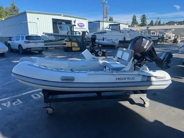 The Image of 2024 Highfield CL340 FCT inflatable boat on a trailer in a marina parking lot. - 2