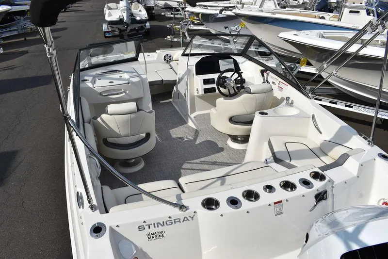 Slide: The Image of 2024 Stingray 201DC boat interior with seating and steering wheel, displayed at a marina. - 12