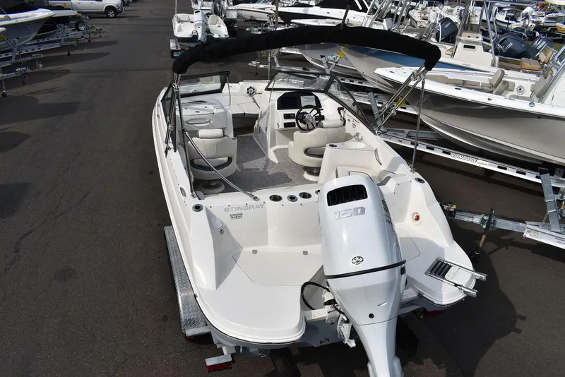 Slide: The Image of 2024 Stingray 201DC boat with outboard motor, parked on a trailer in a marina. - 6