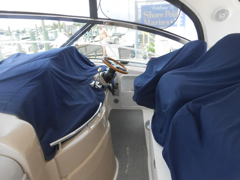 Slide: The Image of Helm area of a 2004 Sea Ray 420 Sundancer with covered seats and steering wheel. - 15