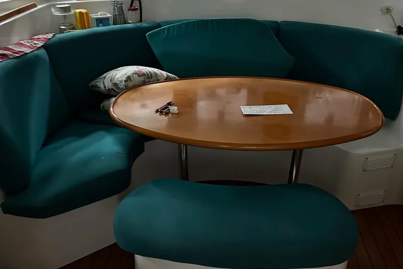 Slide: The Image of Cozy seating area on 2001 Lagoon 380 catamaran with teal cushions and wooden table. - 2