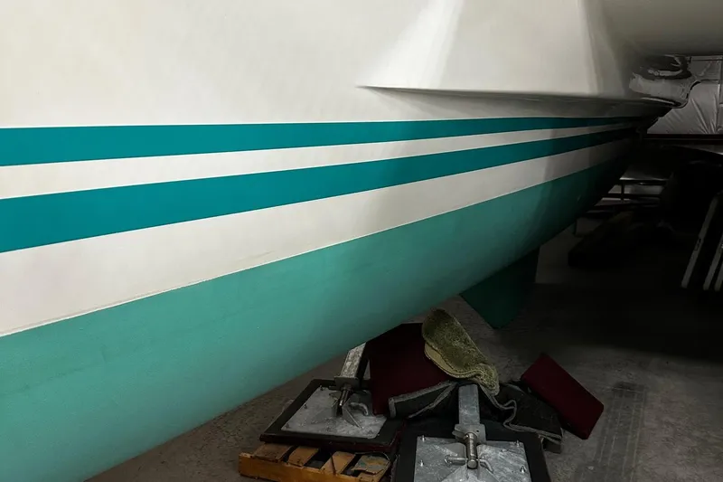 Slide: The Image of 2001 Lagoon 380 catamaran hull with teal and white stripes in a storage area. - 24