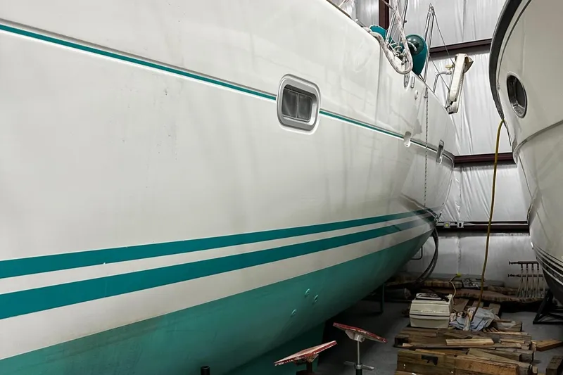 Slide: The Image of 2001 Lagoon 380 catamaran in storage, featuring teal stripes and a white hull. - 26