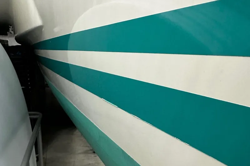 Slide: The Image of Side view of a 2001 Lagoon 380 catamaran with teal and white stripes. - 27
