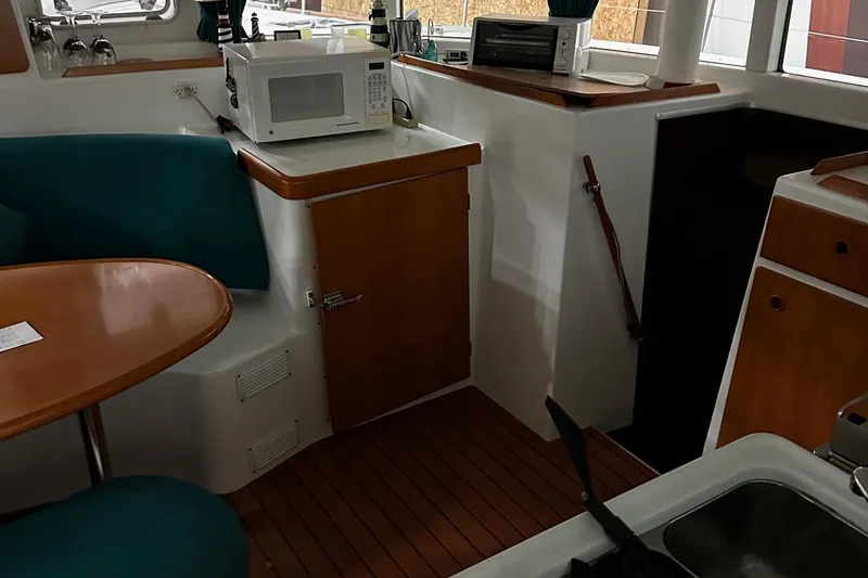 Slide: The Image of Interior of 2001 Lagoon 380 catamaran with microwave, seating, and wooden cabinetry. - 8