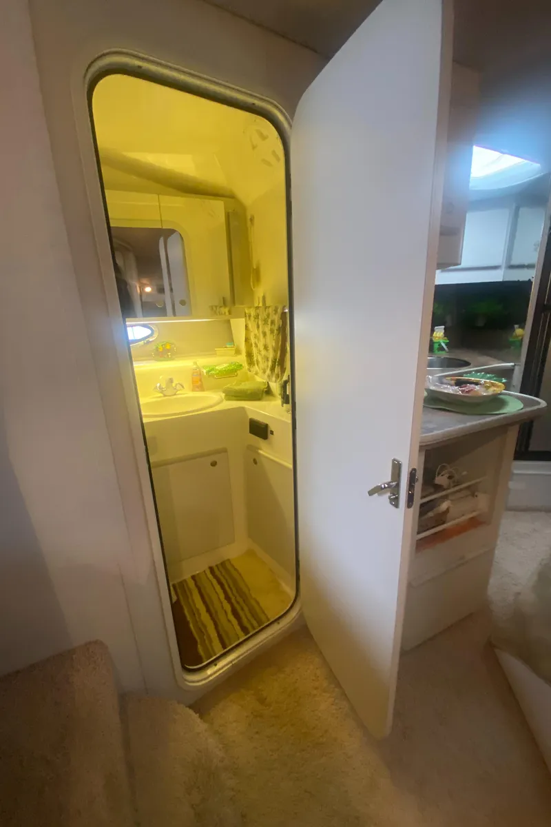 Slide: The Image of 1993 Cruisers 3675 yacht interior with open door to compact bathroom. - 17