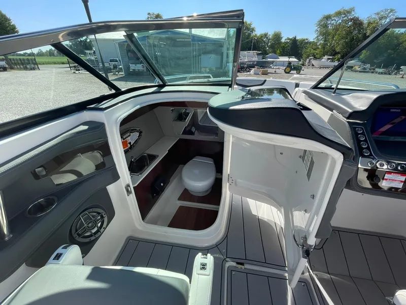 Slide: The Image of 2024 Chaparral 270 OSX boat interior with open cabin door and visible amenities. - 41