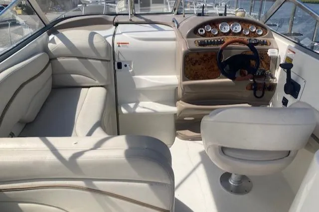 Slide: The Image of 2004 Larson 240 Cabrio boat interior with beige seating and wood-accented dashboard. - 5