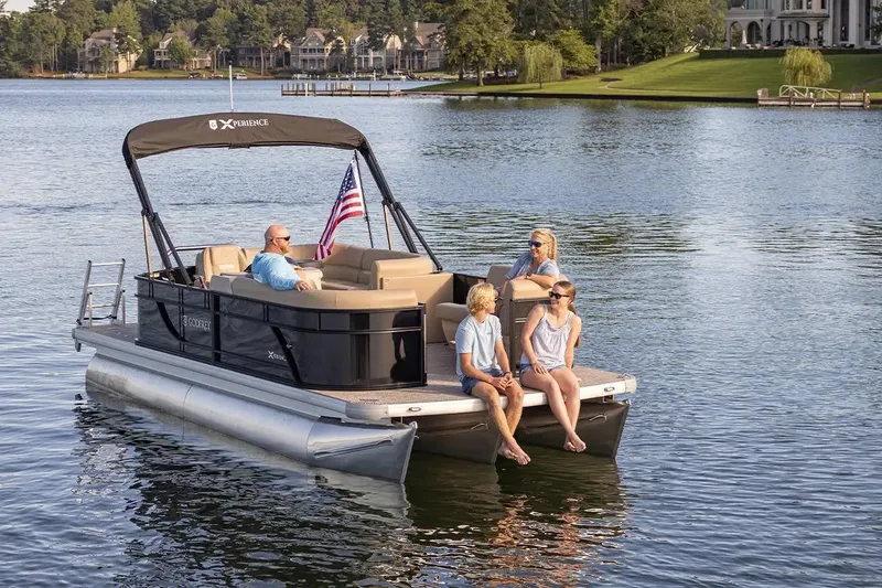 Slide: The Image of 2024 Sweetwater 2086 CX pontoon boat on a serene lake with passengers enjoying the view. - 6