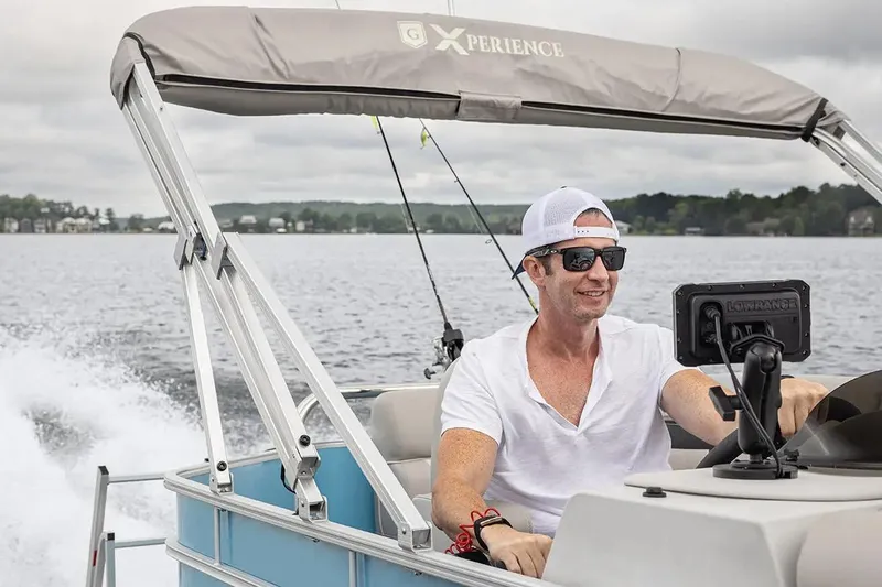 Slide: The Image of Man piloting 2024 Sweetwater 2086 CX boat on a lake, wearing sunglasses and a cap. - 9