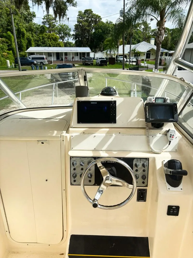 Slide: The Image of 2005 Key West 2300 Walkaround boat helm with steering wheel and navigation equipment. - 2