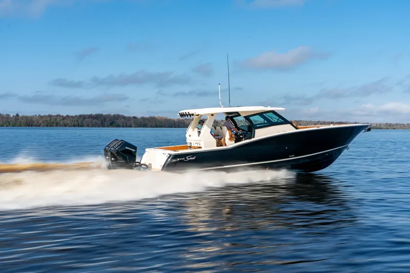 Slide: The Image of 2026 Scout 425 LXF boat cruising on a calm lake under a clear blue sky. - 2