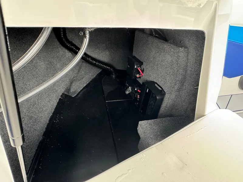 Slide: The Image of 2024 Malibu Wakesetter 21 LX storage compartment with wiring and battery. - 22