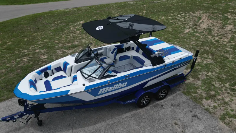Slide: The Image of 2024 Malibu Wakesetter 21 LX boat with blue and white design on a trailer. - 3