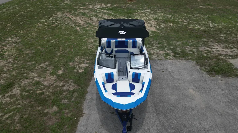 Slide: The Image of 2024 Malibu Wakesetter 21 LX boat, top view, blue and white design, parked on grass. - 9