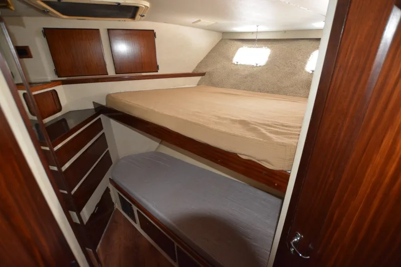 Slide: The Image of 1989 Hatteras Cockpit Motoryacht cabin with wooden interior and cozy sleeping area. - 14