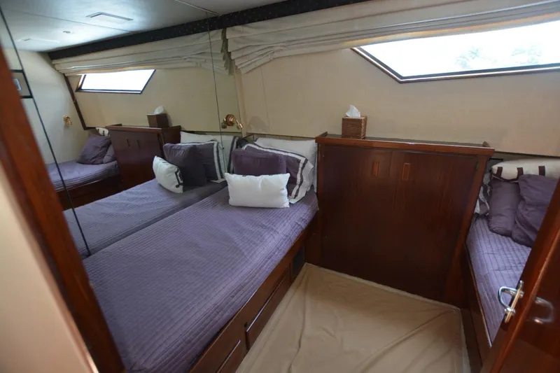 Slide: The Image of 1989 Hatteras Cockpit Motoryacht bedroom with twin beds and elegant wood paneling. - 16