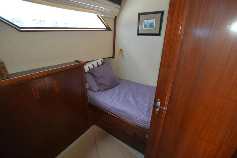 Slide: The Image of 1989 Hatteras Cockpit Motoryacht cabin with wooden interior and single bed. - 17