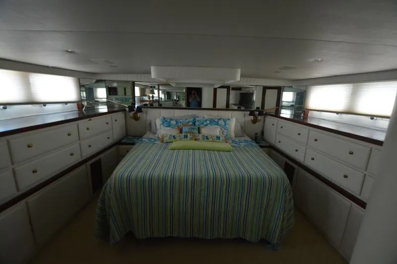 Slide: The Image of Luxurious bedroom interior of 1989 Hatteras Cockpit Motoryacht with striped bedding and ample storage. - 21