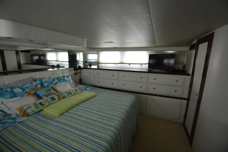Slide: The Image of Luxurious bedroom in 1989 Hatteras Cockpit Motoryacht with striped bedding and ample storage. - 23