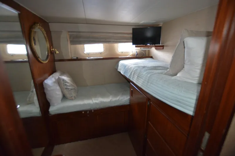 Slide: The Image of 1989 Hatteras Cockpit Motoryacht cabin with twin beds, TV, and wooden interior. - 27