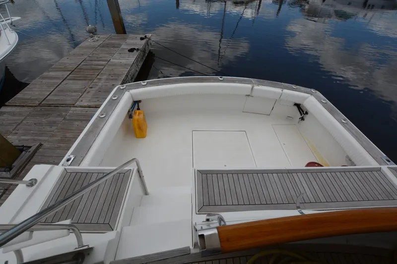 Slide: The Image of 1989 Hatteras Cockpit Motoryacht docked, featuring spacious deck and wooden accents. - 5