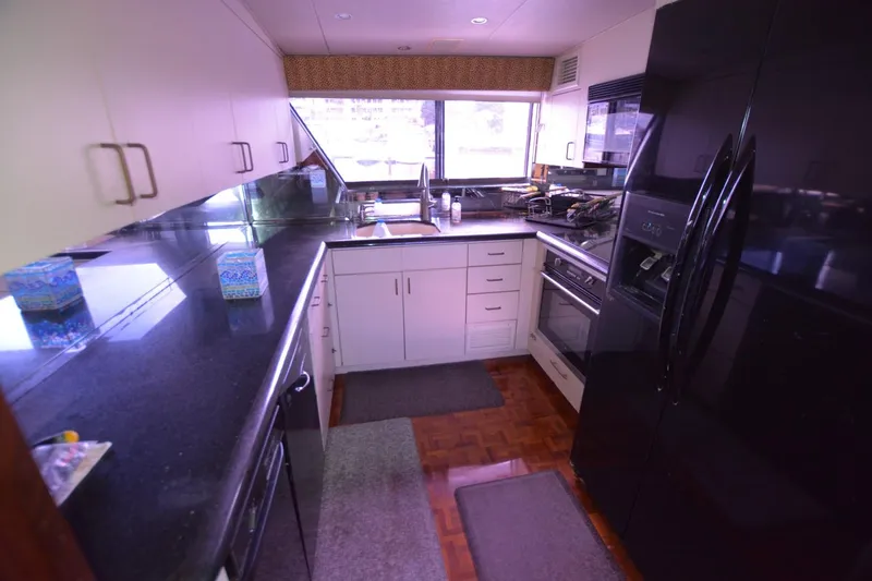 Slide: The Image of 1989 Hatteras Cockpit Motoryacht kitchen with black countertops and modern appliances. - 9
