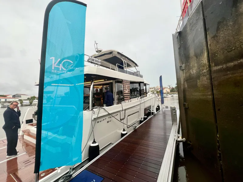 Slide: The Image of 2025 Beneteau Swift Trawler 54 docked at marina, side view. - 1
