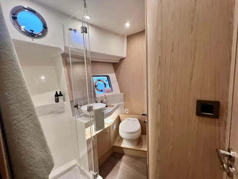 Slide: The Image of Modern bathroom on 2025 Beneteau Swift Trawler 54 with shower, toilet, and porthole window. - 14