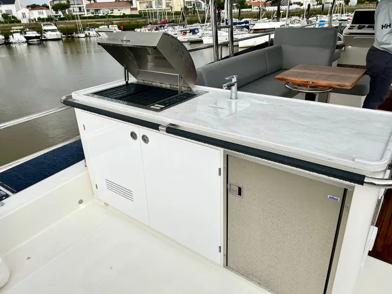 Slide: The Image of Outdoor kitchen on the 2025 Beneteau Swift Trawler 54 yacht, featuring a grill and sink. - 25