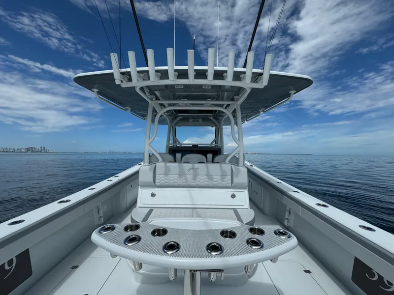 Slide: The Image of 2024 Yellowfin 39 boat interior with rod holders and seating, on calm ocean water. - 16