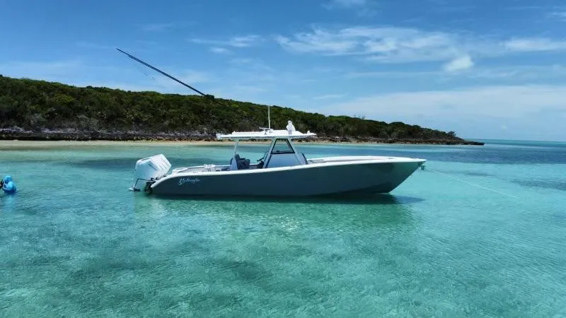 Slide: The Image of 2024 Yellowfin 39 boat anchored in clear turquoise water near a lush island. - 8