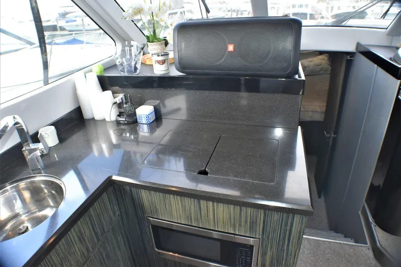 Slide: The Image of Modern kitchen area in 2019 Silverton 41 Sport Bridge yacht with sink, stove, and microwave. - 36