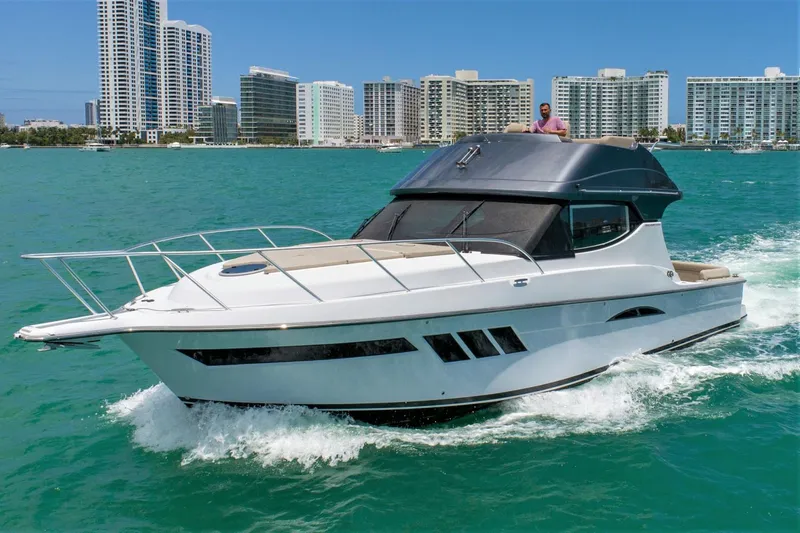 Slide: The Image of 2019 Silverton 41 Sport Bridge yacht cruising in turquoise waters near city skyline. - 4