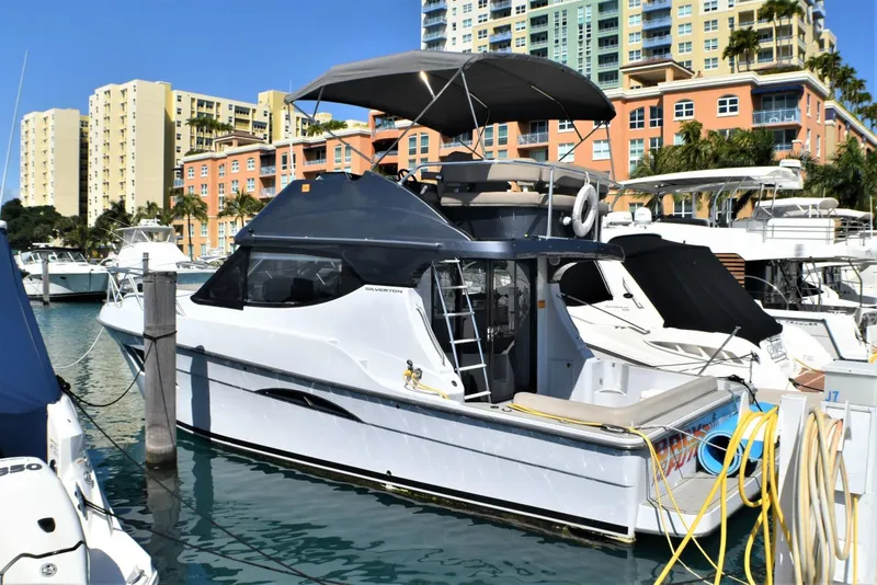 Slide: The Image of 2019 Silverton 41 Sport Bridge yacht docked in a marina with cityscape background. - 48