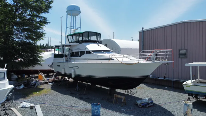 The Image of 1998 Mainship 47 Motor Yacht on dry dock, surrounded by equipment and buildings. - 0