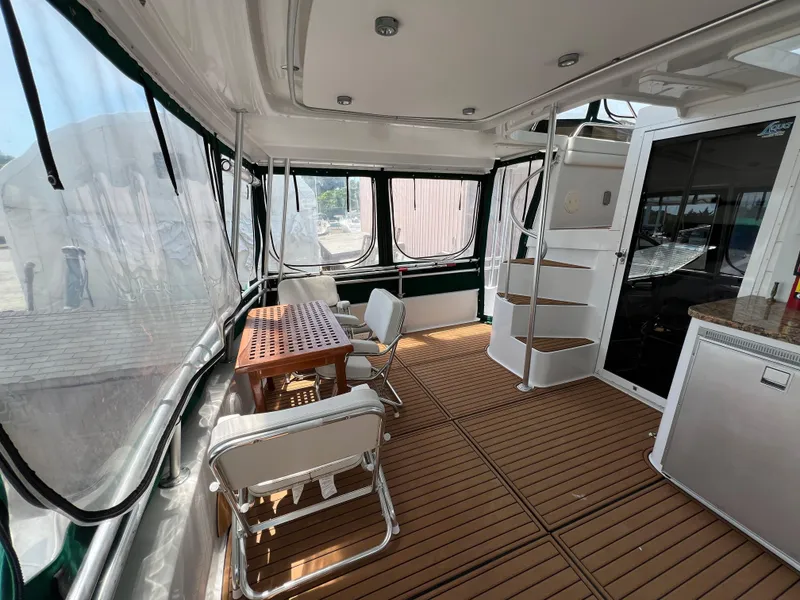 Slide: The Image of 1998 Mainship 47 Motor Yacht interior with wooden flooring, table, chairs, and spiral staircase. - 13