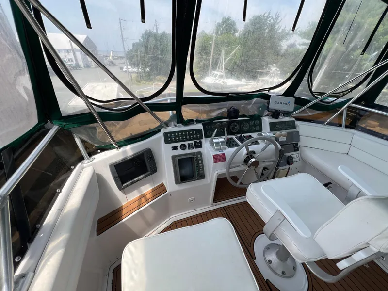 Slide: The Image of 1998 Mainship 47 Motor Yacht helm with steering wheel, navigation equipment, and seating. - 18