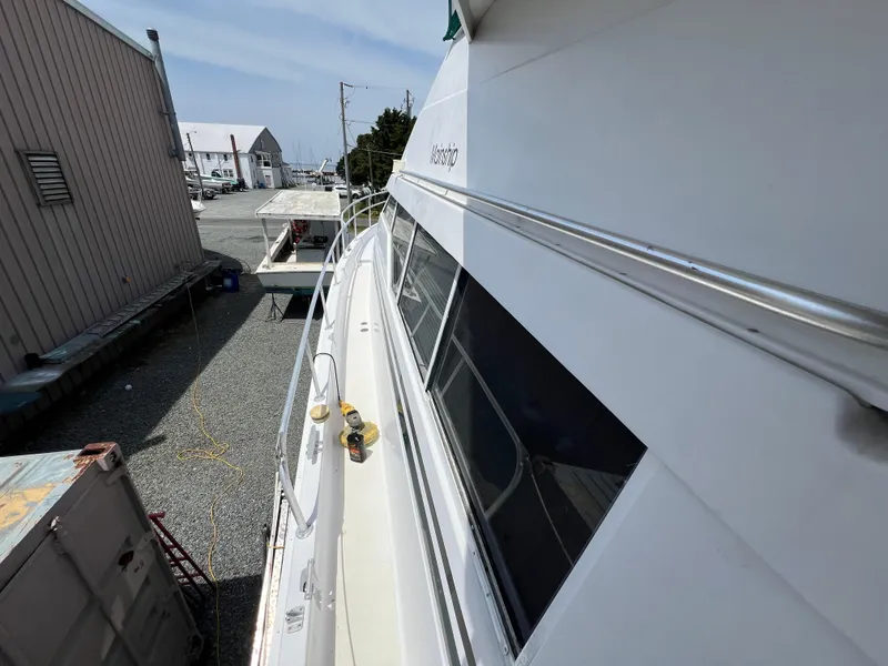 Slide: The Image of 1998 Mainship 47 Motor Yacht docked, side view with windows and railing visible. - 28