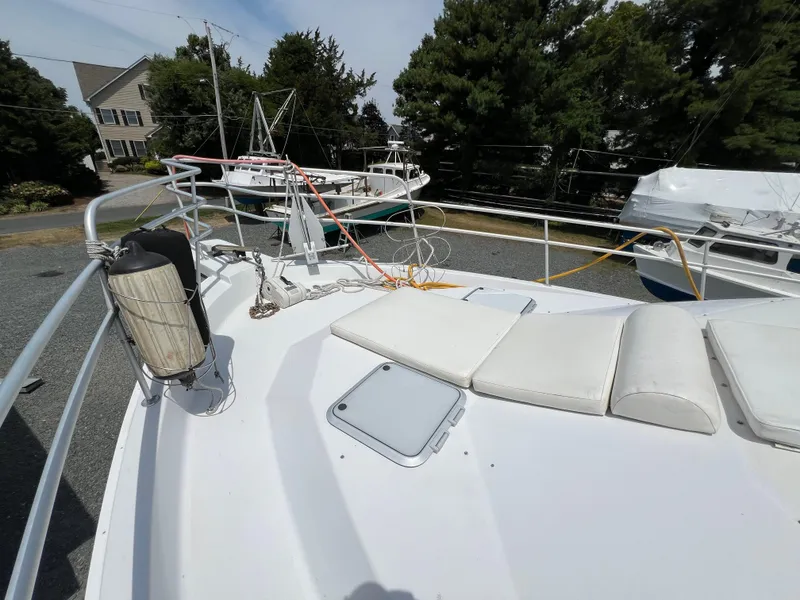 Slide: The Image of 1998 Mainship 47 Motor Yacht deck with seating and railing, surrounded by trees and other boats. - 31