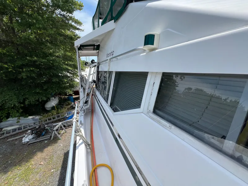 Slide: The Image of 1998 Mainship 47 Motor Yacht side view with trees and equipment in the background. - 35