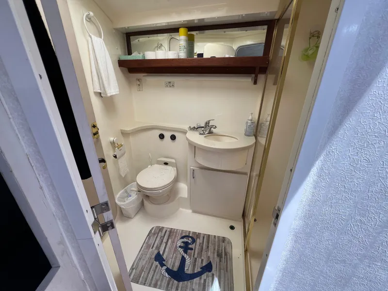 Slide: The Image of Bathroom interior of 1998 Mainship 47 Motor Yacht with toilet, sink, and nautical-themed mat. - 38