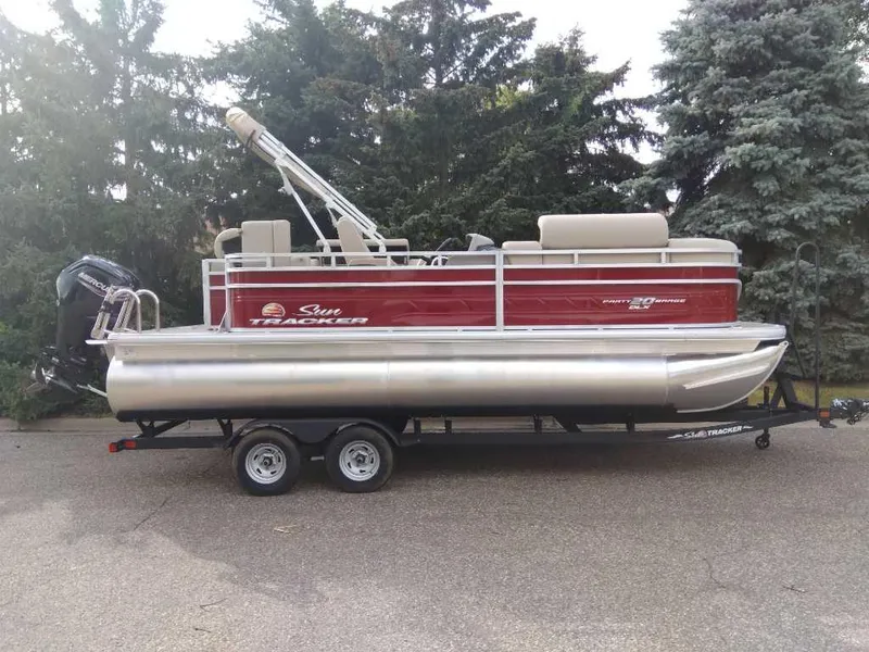 The Image of 2024 Sun Tracker Party Barge 20 DLX pontoon boat on trailer, parked outdoors. - 0