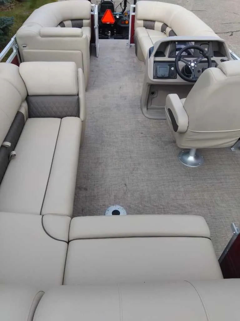 Slide: The Image of 2024 Sun Tracker Party Barge 20 DLX interior with beige seating and steering console. - 10