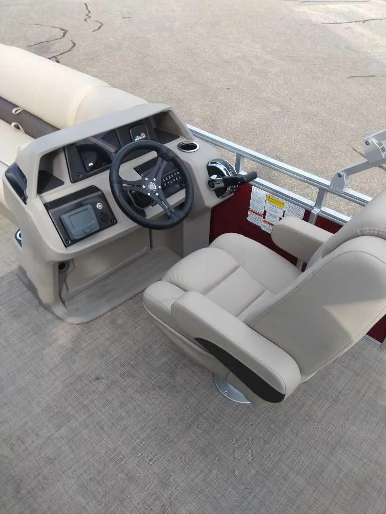 Slide: The Image of 2024 Sun Tracker Party Barge 20 DLX helm with beige captain's chair and control panel. - 9