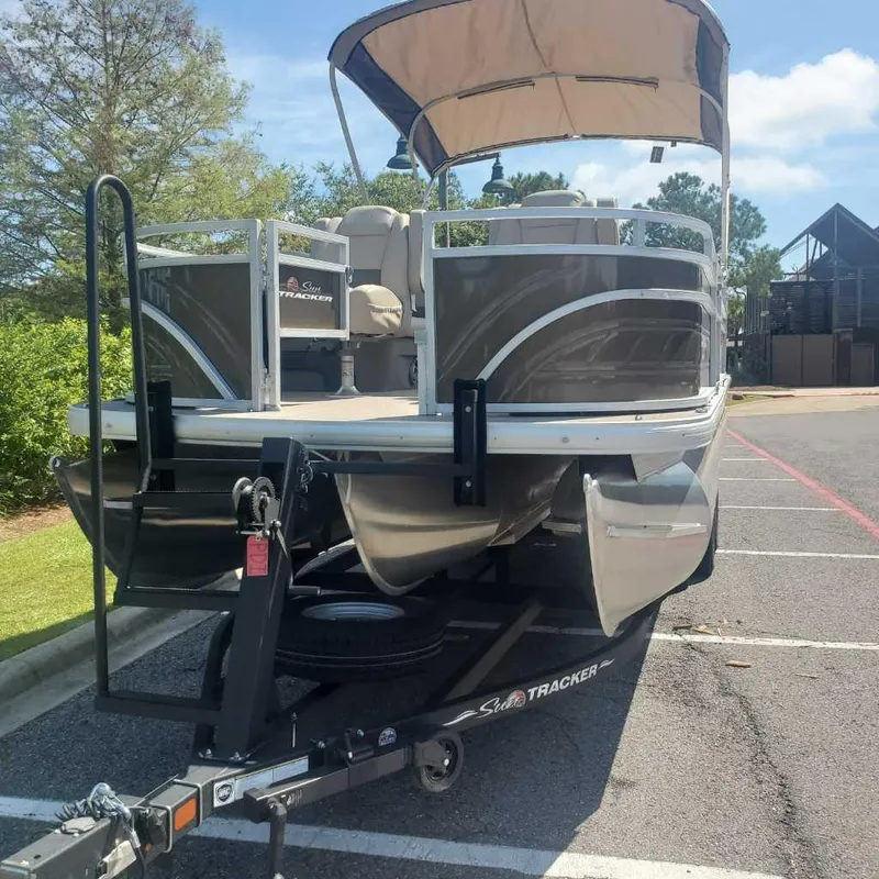 Slide: The Image of 2024 Sun Tracker Sportfish 24 XP3 pontoon boat on a trailer in a parking lot. - 2