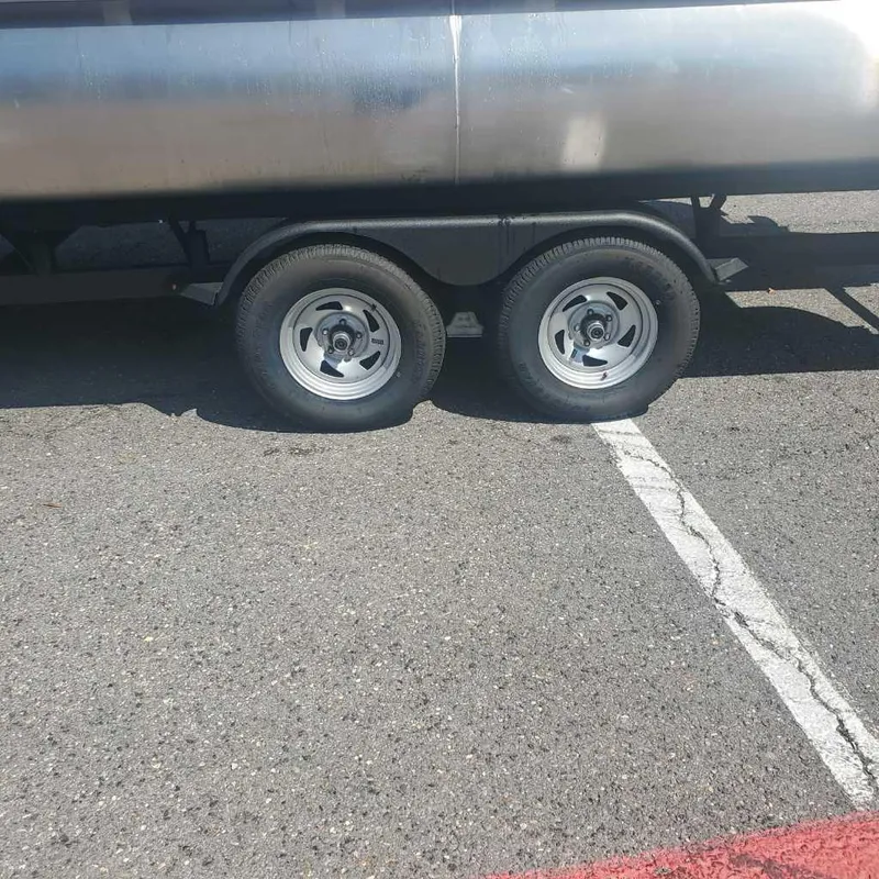 Slide: The Image of Trailer of a 2024 Sun Tracker Sportfish 24 XP3 pontoon boat in a parking lot. - 6