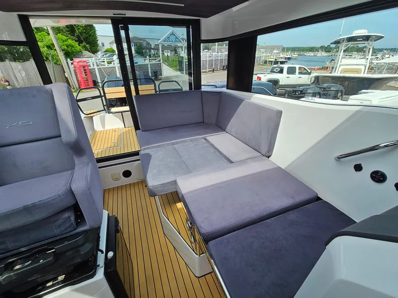 Slide: The Image of 2023 XO Boats EXPLR 10 Sport Plus interior with grey seating and wooden flooring. - 23