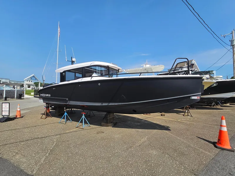 Slide: The Image of 2023 XO Boats EXPLR 10 Sport Plus on display, black hull, docked on land. - 6